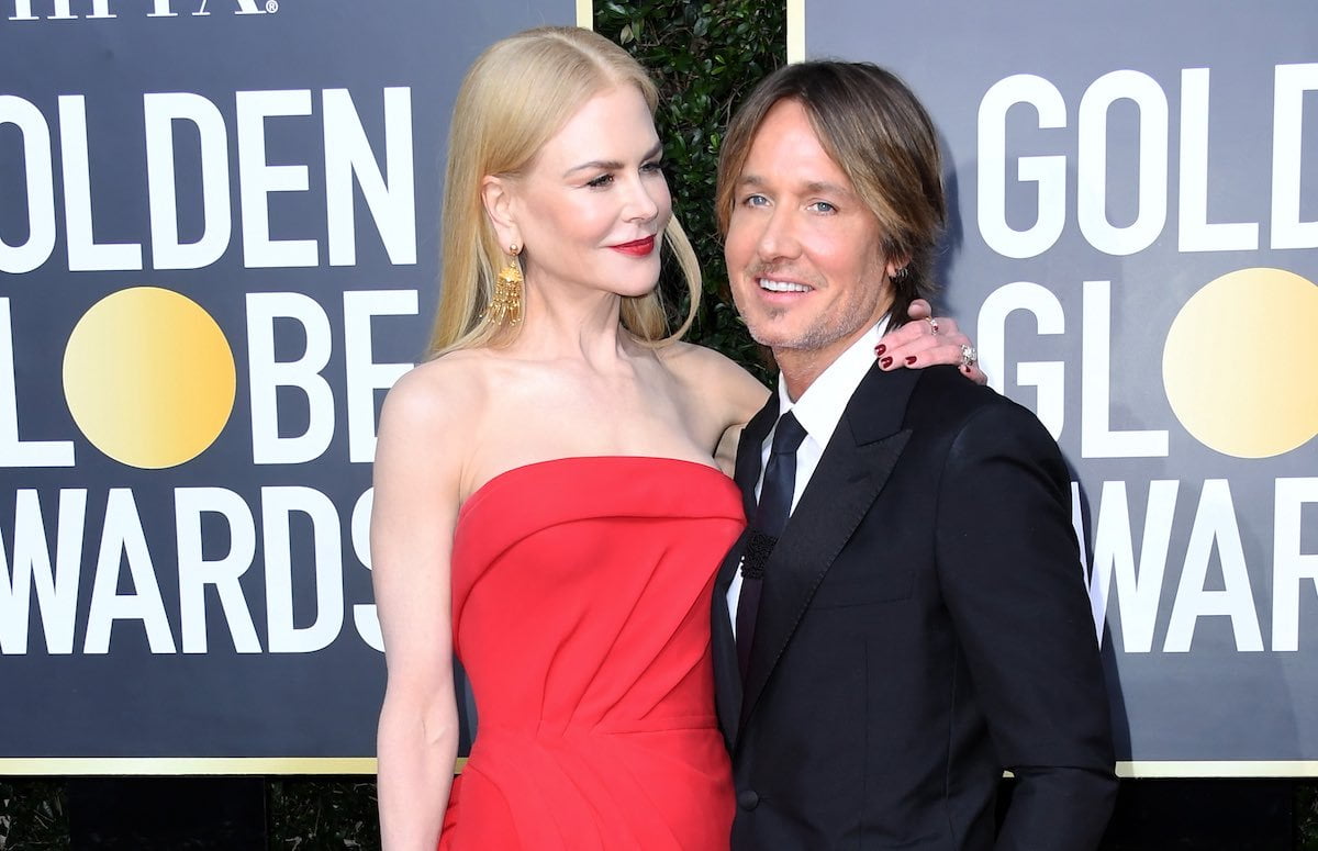 Nicole Kidman in a red dress smiles at Keith Urban in a suit
